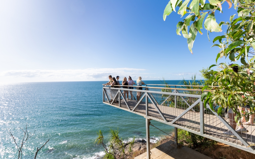 Visitors standing on the Flagstaff Hill Lookout viewing platform overlooking the Coral Sea and the coastline of Port Douglas.