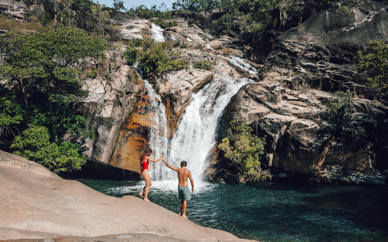 Couple beside the clear swimming hole and cascading water at Emerald Creek Falls near Mareeba in Tropical North Queensland.