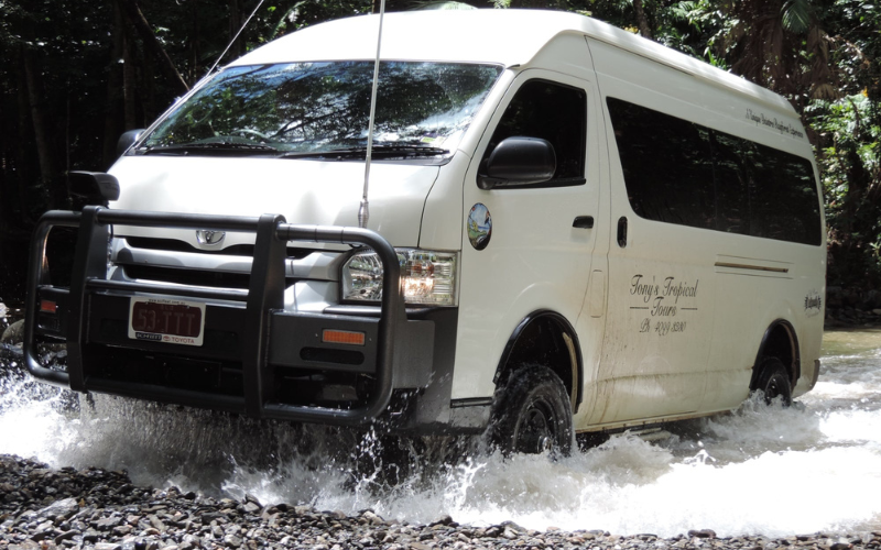White Tony's Tropical Tours 4WD minibus driving through a shallow rainforest creek on a guided Daintree Rainforest tour from Port Douglas.